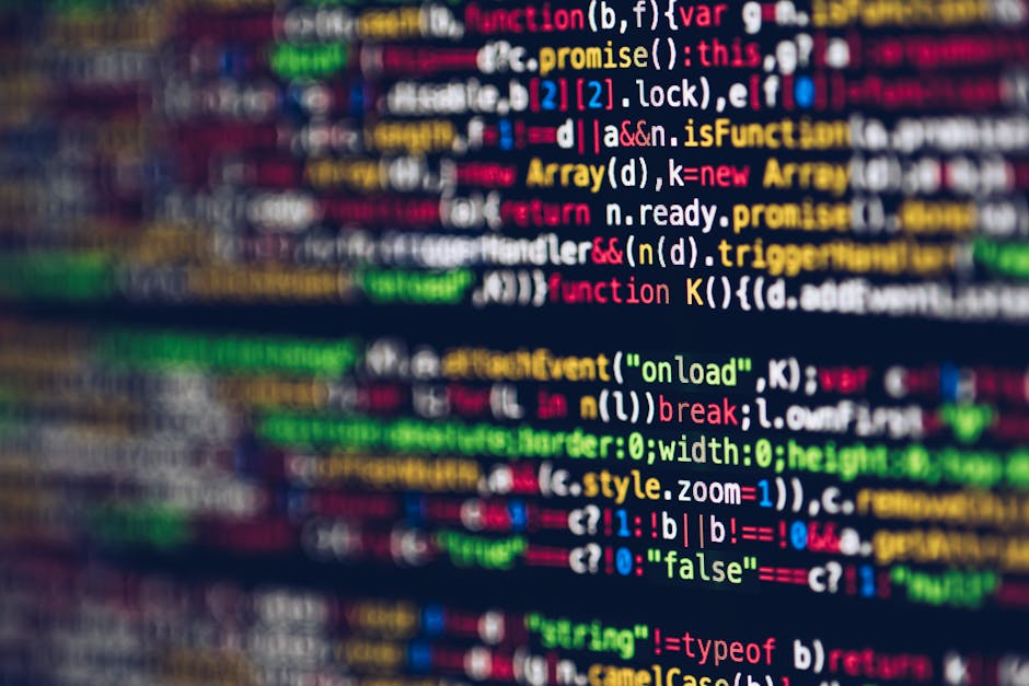 A close-up digital photograph of a computer screen displaying lines of colorful programming code with syntax highlighting, including keywords, variables, and functions in shades of red, green, yellow,